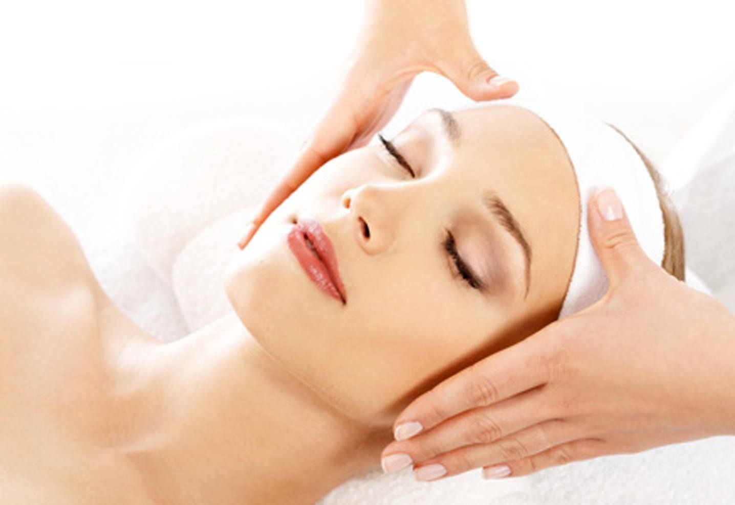 Woman receiving a facial massage, eyes closed, hands on her face.