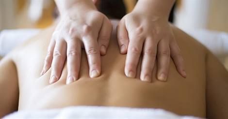 Hands massaging a person's bare back in a spa setting, promoting relaxation and well-being.