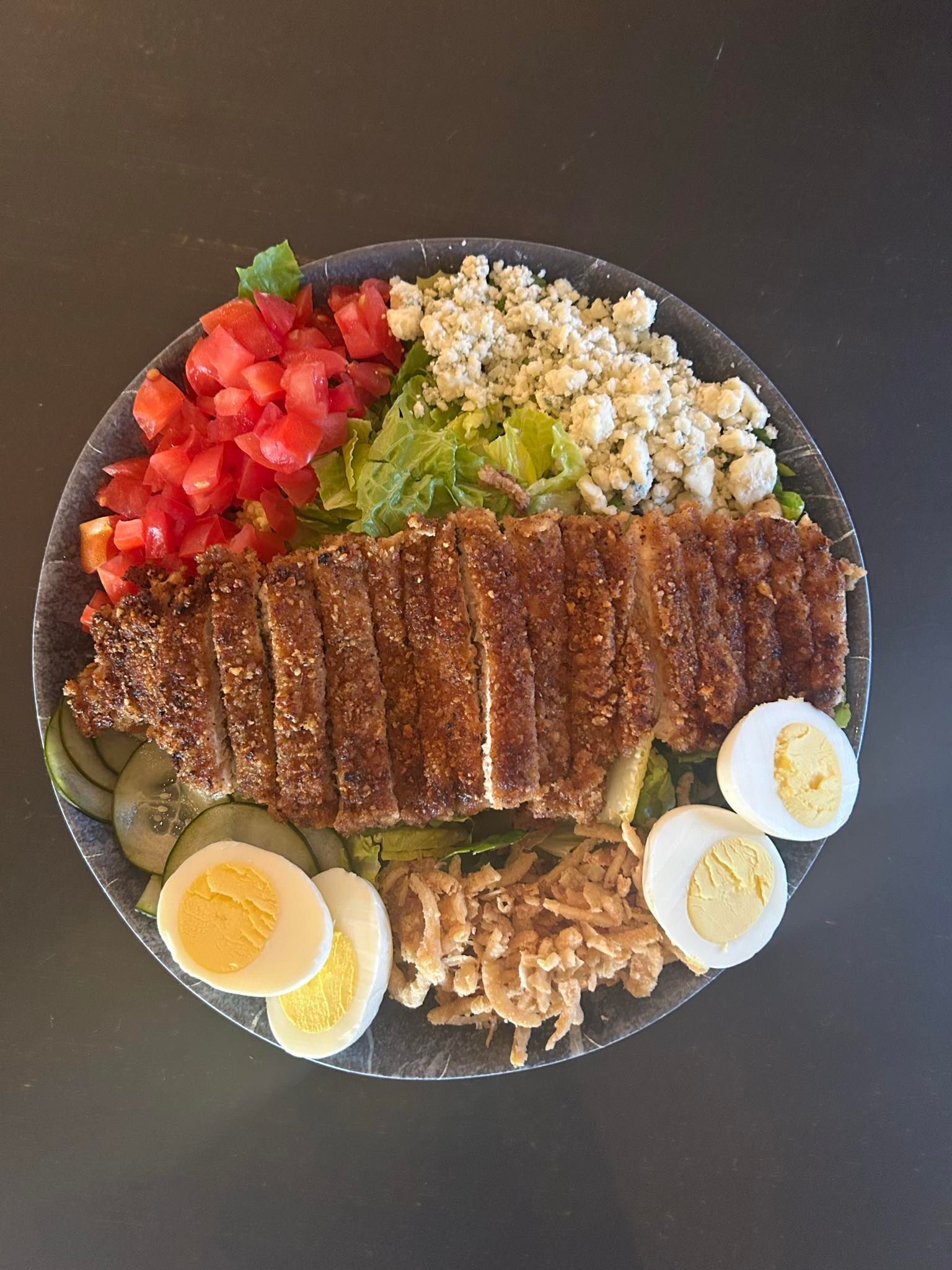 A plate of food with meat , eggs , tomatoes and lettuce on a table.