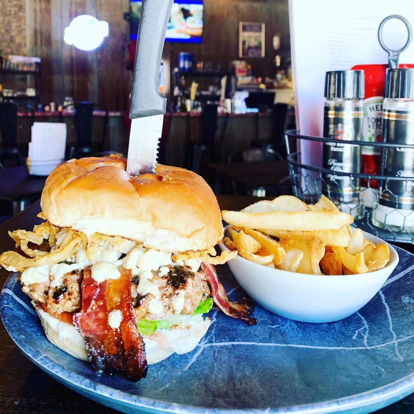 A hamburger and a bowl of french fries on a plate