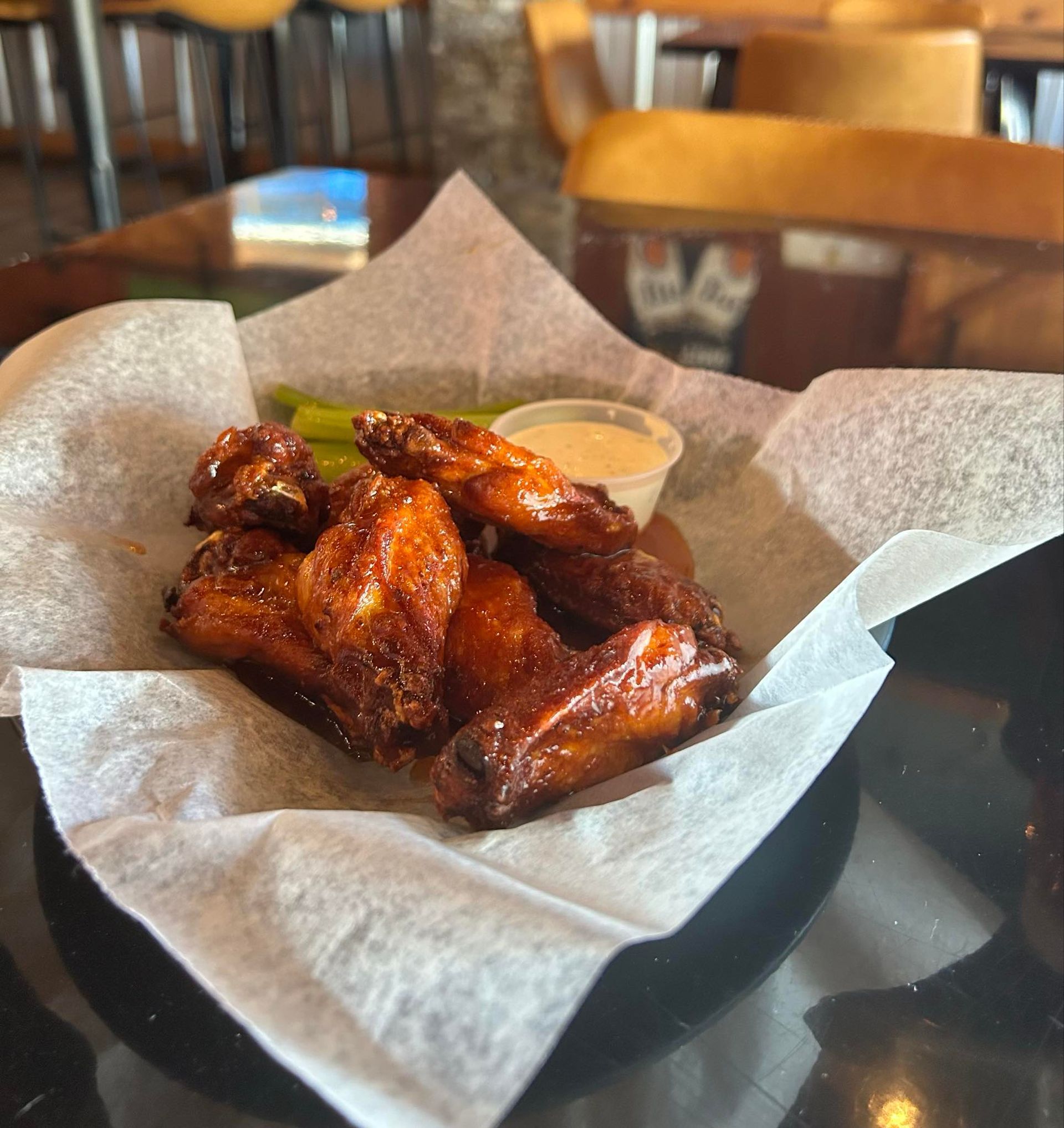 A bowl of chicken wings with dipping sauce on a napkin on a table.