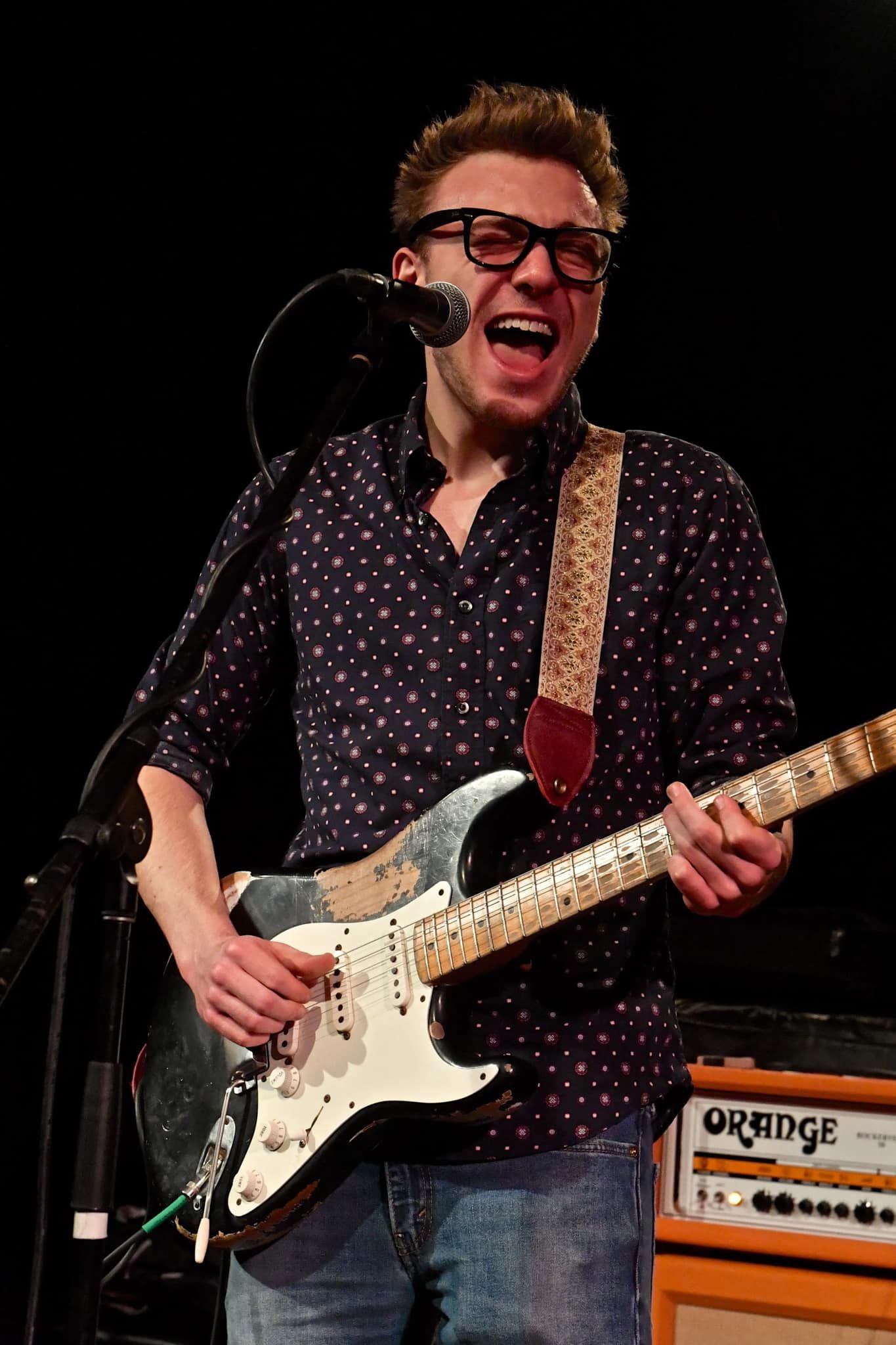 A man is playing a guitar and singing into a microphone on stage.