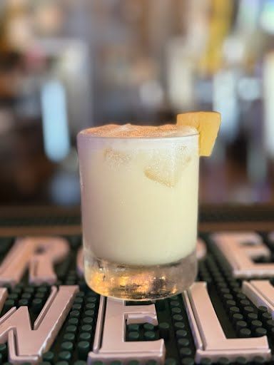 A close up of a drink in a glass on a bar.
