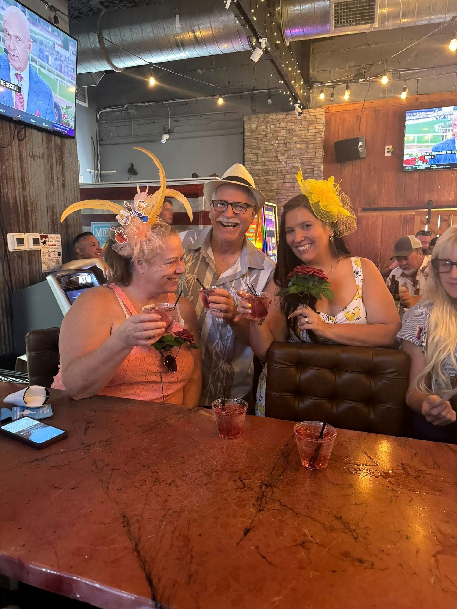 A group of people are sitting at a table in a restaurant holding drinks.