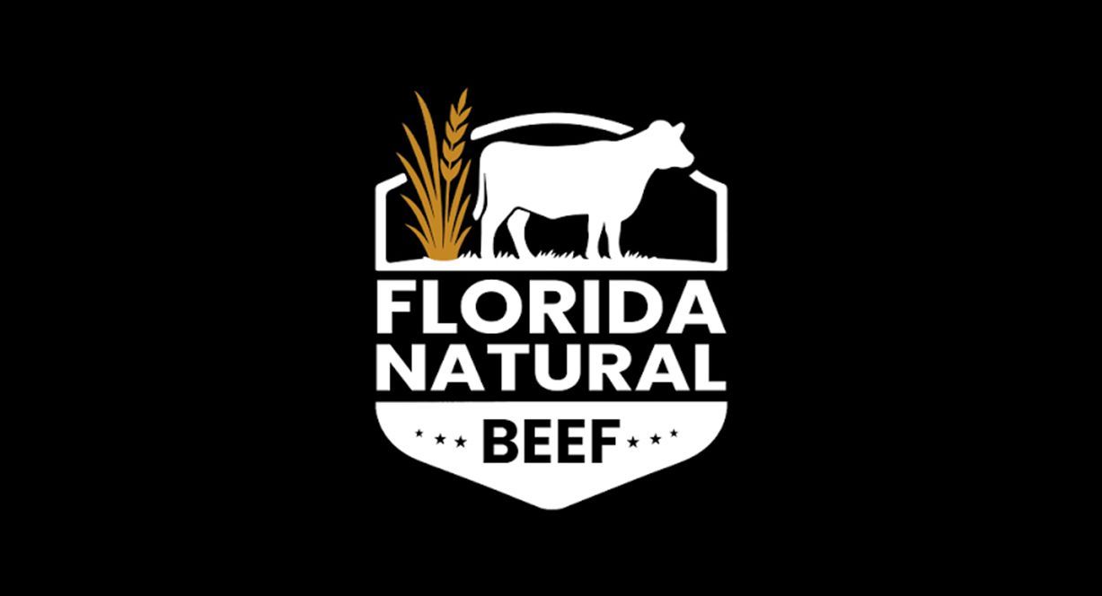 A white shield-shaped logo featuring a silhouette of a cow, wheat stalks, and the text 