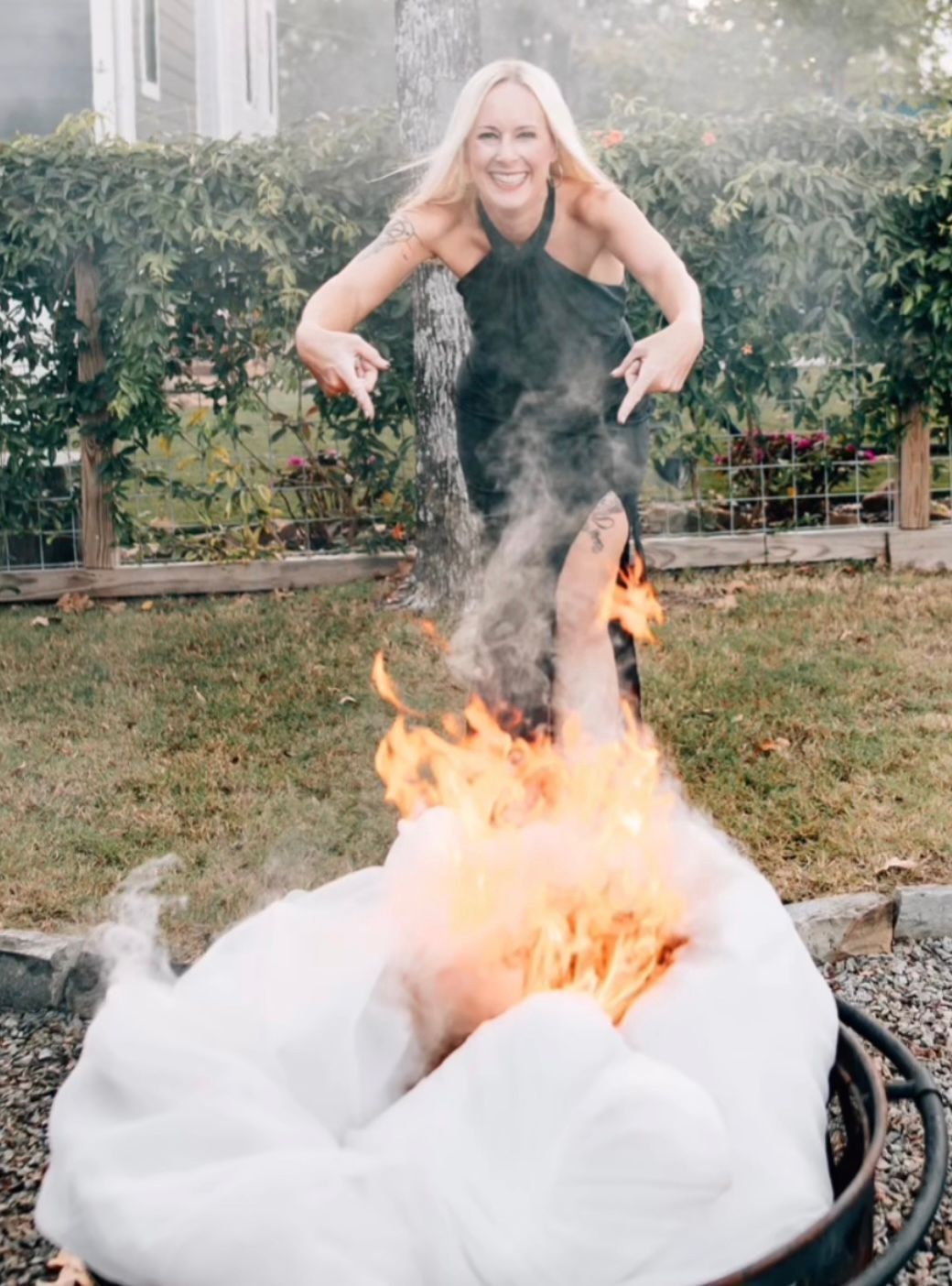 A woman in a black dress is standing next to a fire