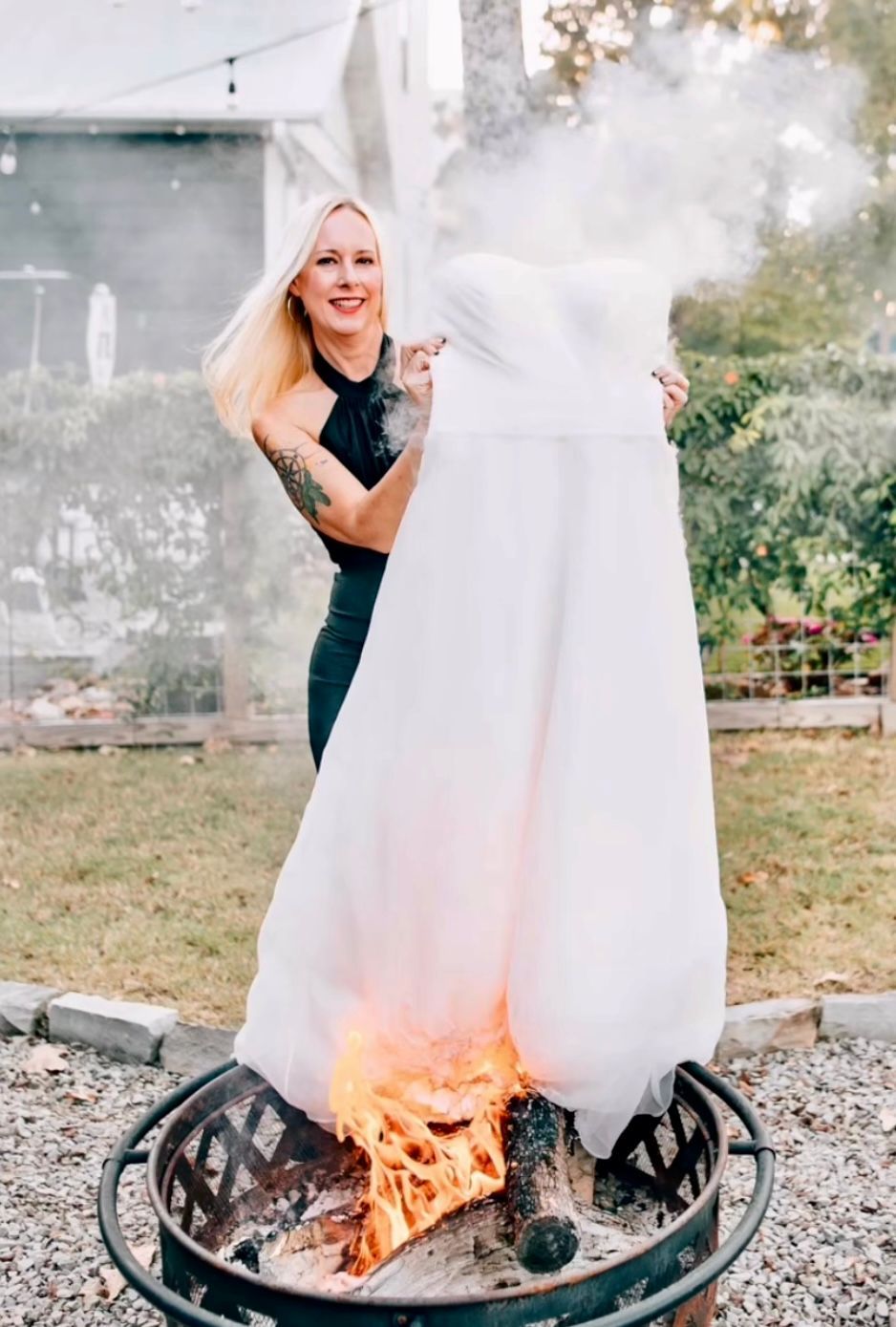 A woman is holding a white sheet over a fire pit.