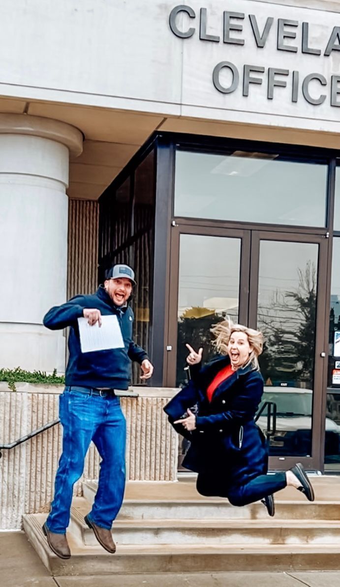 A man and a woman are jumping in the air in front of the cleveland office
