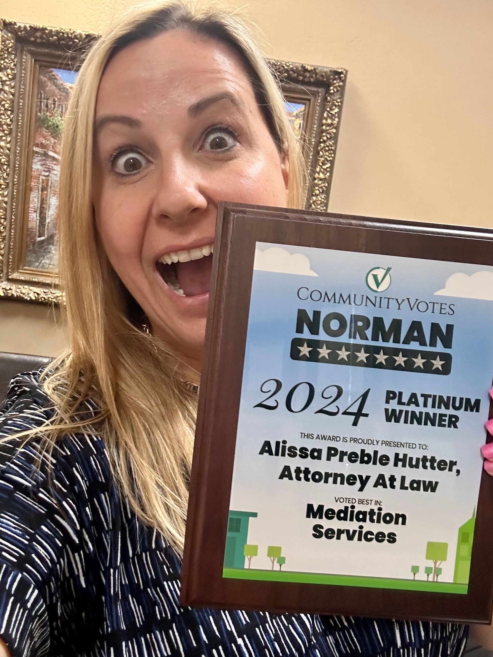 A woman is holding a plaque that says norman platinum winner 2024