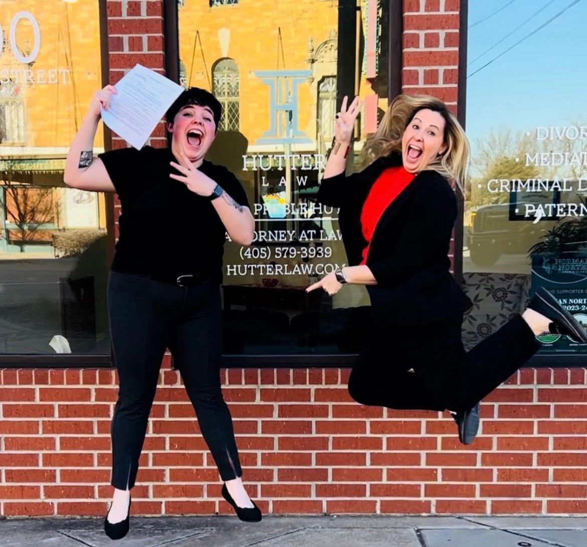 Two women are jumping in the air in front of a brick building