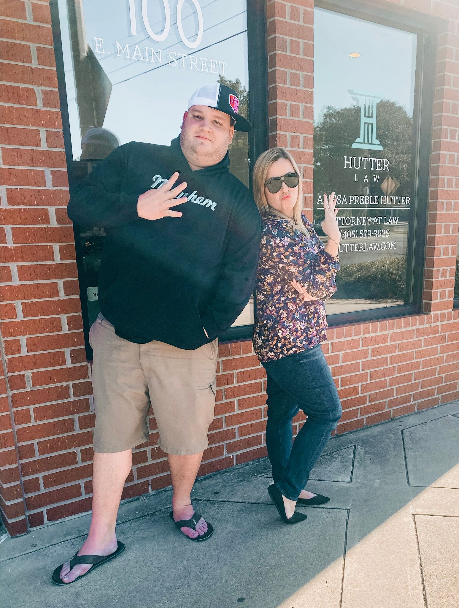 A man and a woman are standing in front of a brick building.