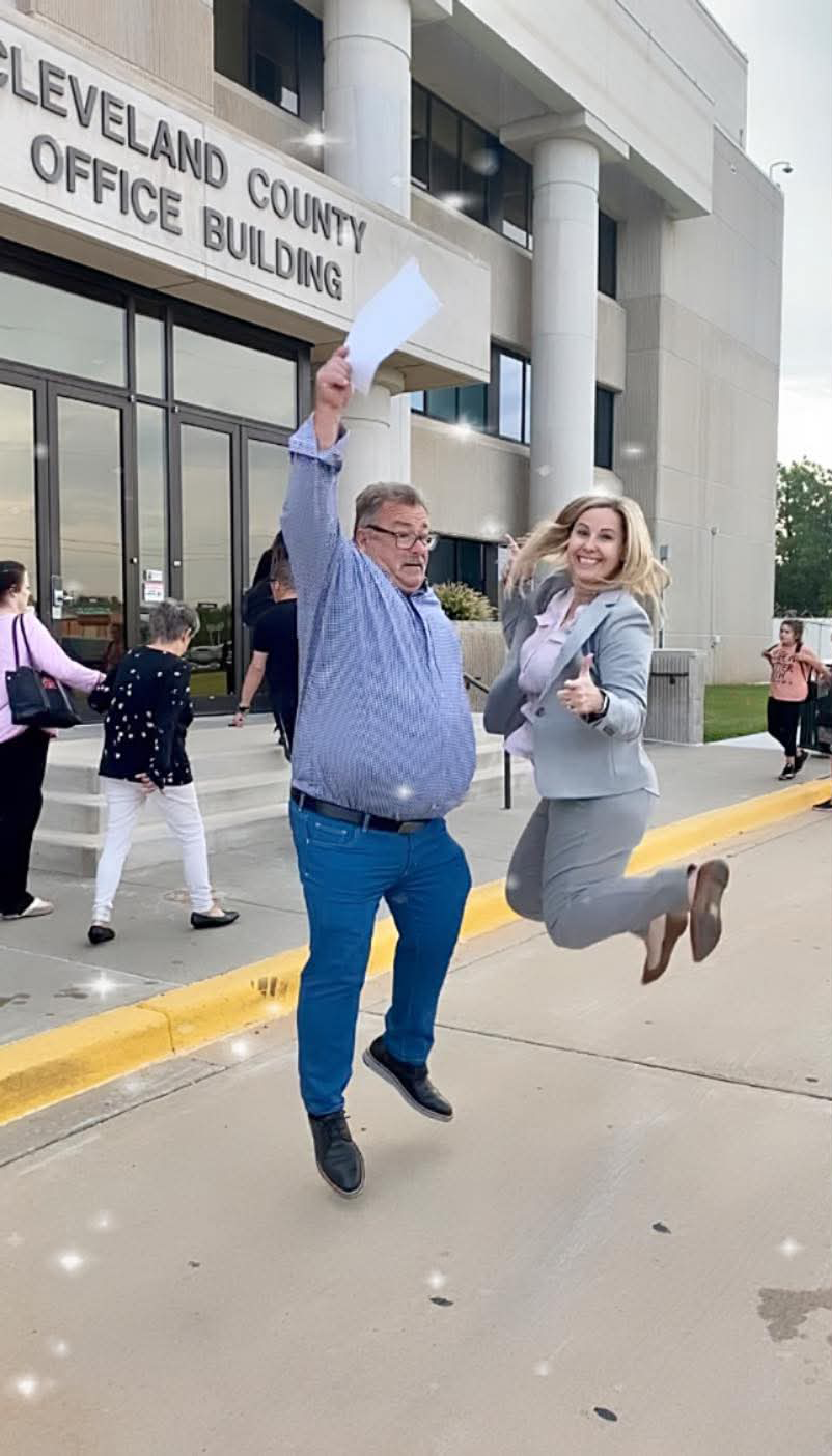 A man and a woman are jumping in the air in front of a building.