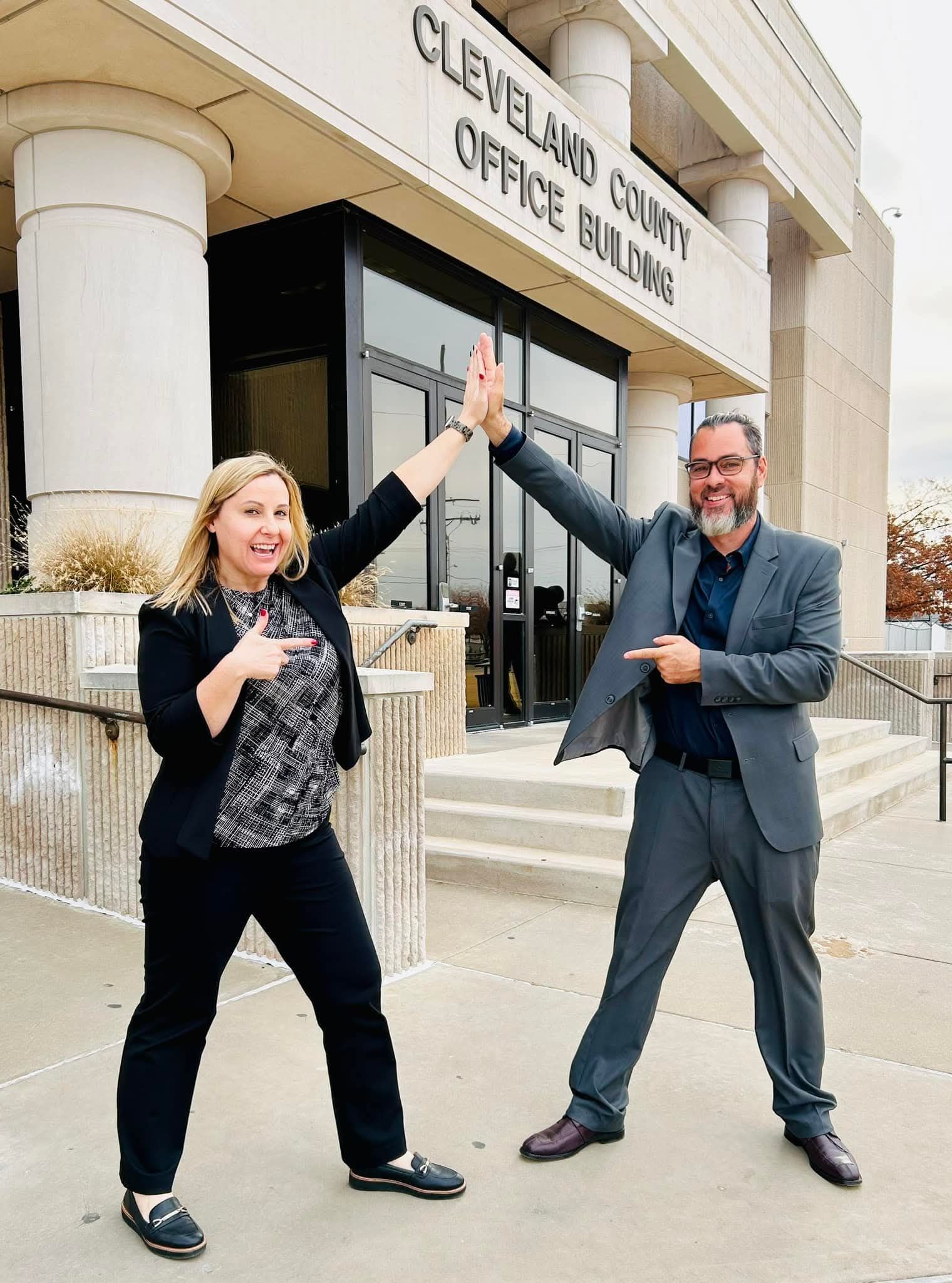 A man and a woman are giving each other a high five in front of a building.