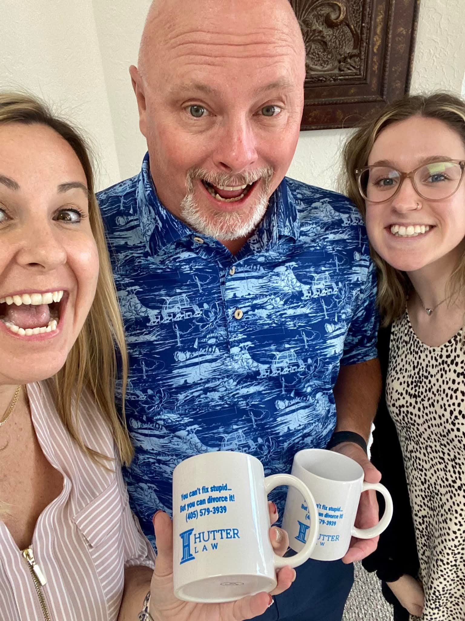 A man and two women are holding coffee mugs and smiling for a picture.