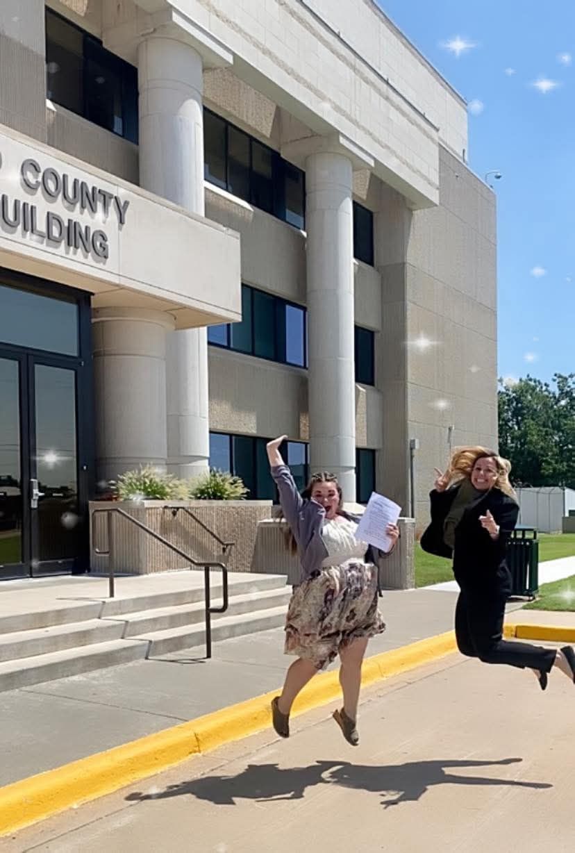 Two women are jumping in the air in front of a building.