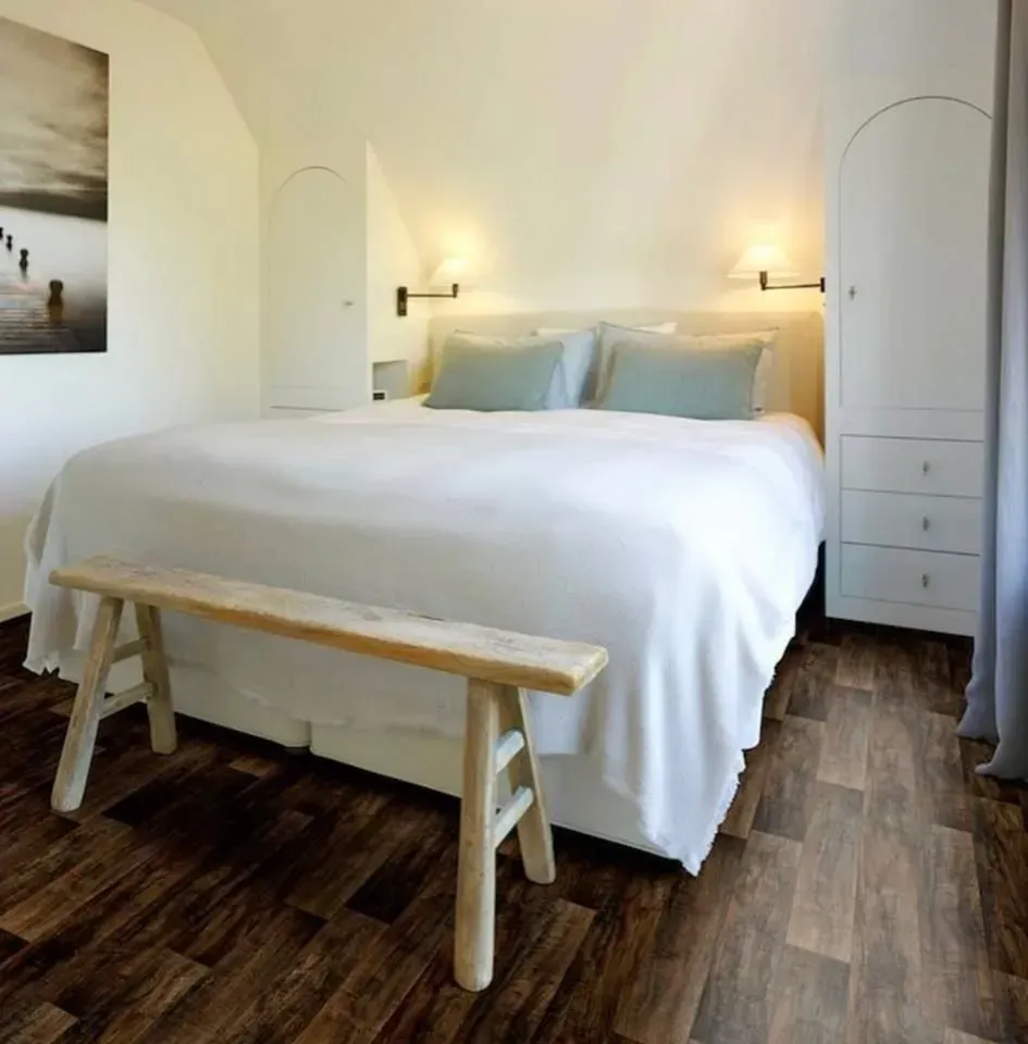 A bedroom with a large bed and a wooden bench