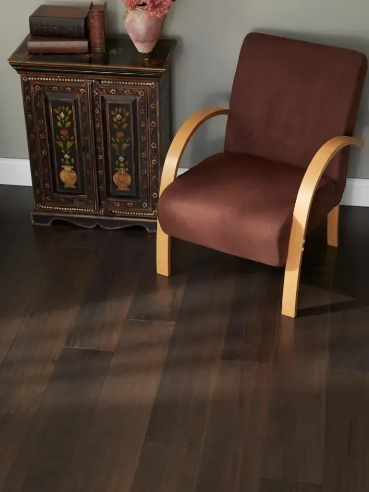 A brown chair sits on a wooden floor next to a dresser