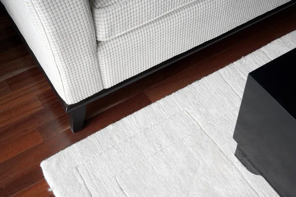 A living room with a white couch and a white rug