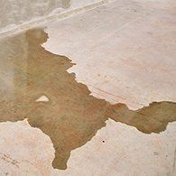 Brown liquid stain on a light-colored concrete surface.