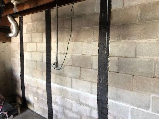 Concrete block wall with black vertical strips for structural reinforcement.