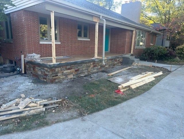 House porch under construction, with stone veneer and wooden framing.