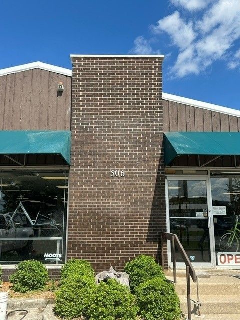 Brick facade with store front; teal awnings, shop windows, and brown building siding.
