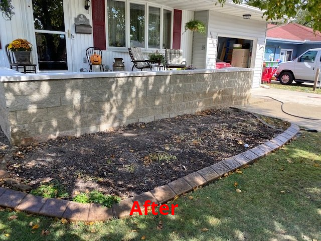 Front yard with freshly edged flower bed next to a house with a raised porch.