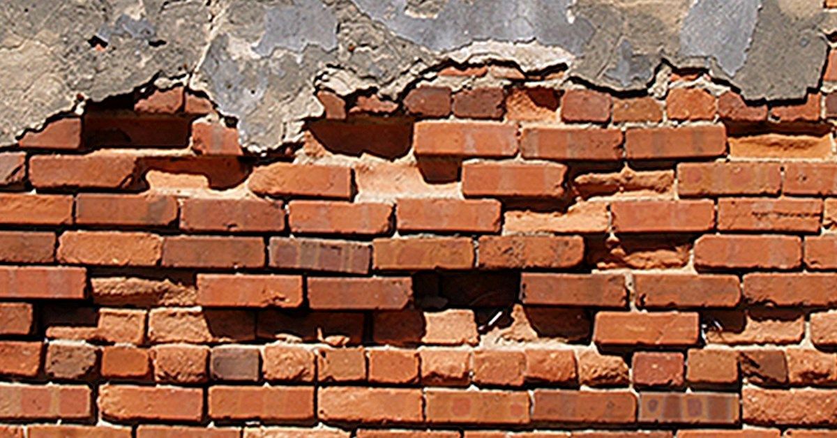 Weathered red brick wall with crumbling plaster.