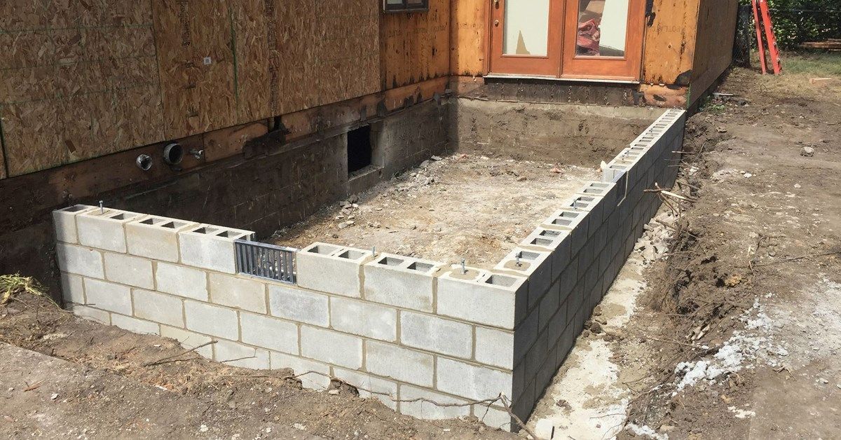 Foundation construction site; cinder block retaining wall built against wooden structure and earth.