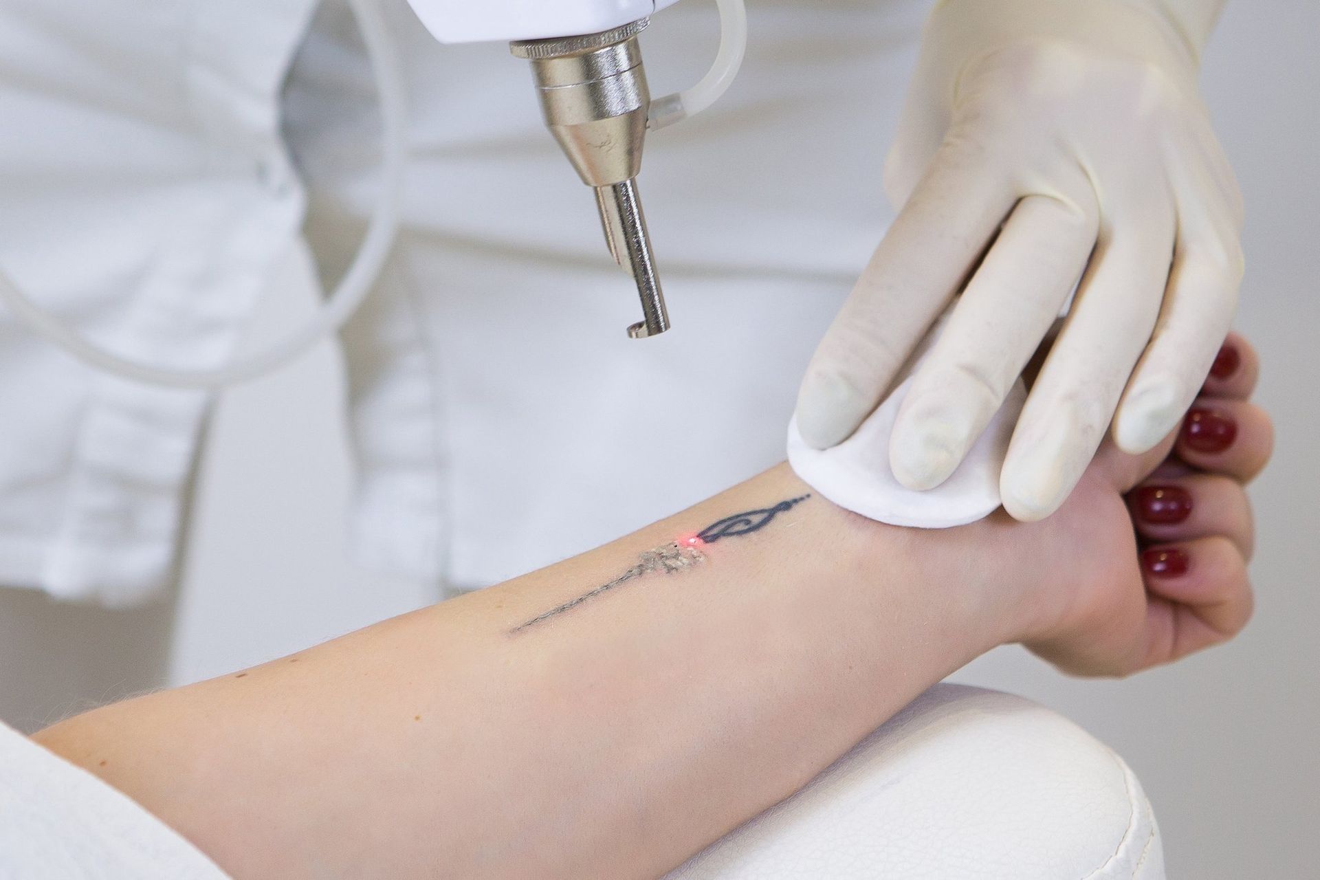Healthcare worker treating a forearm wound with a medical tool and gloved hands
