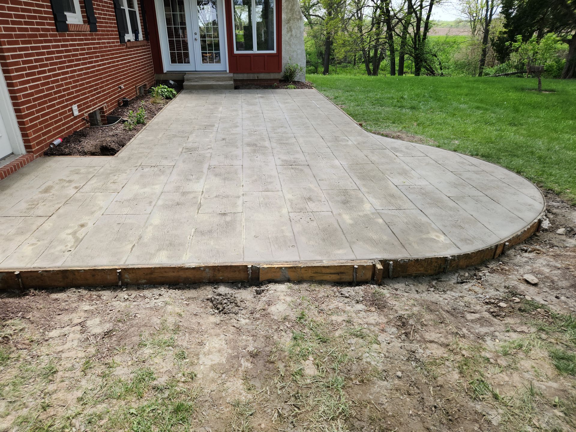 a concrete patio is being built in front of a brick house .