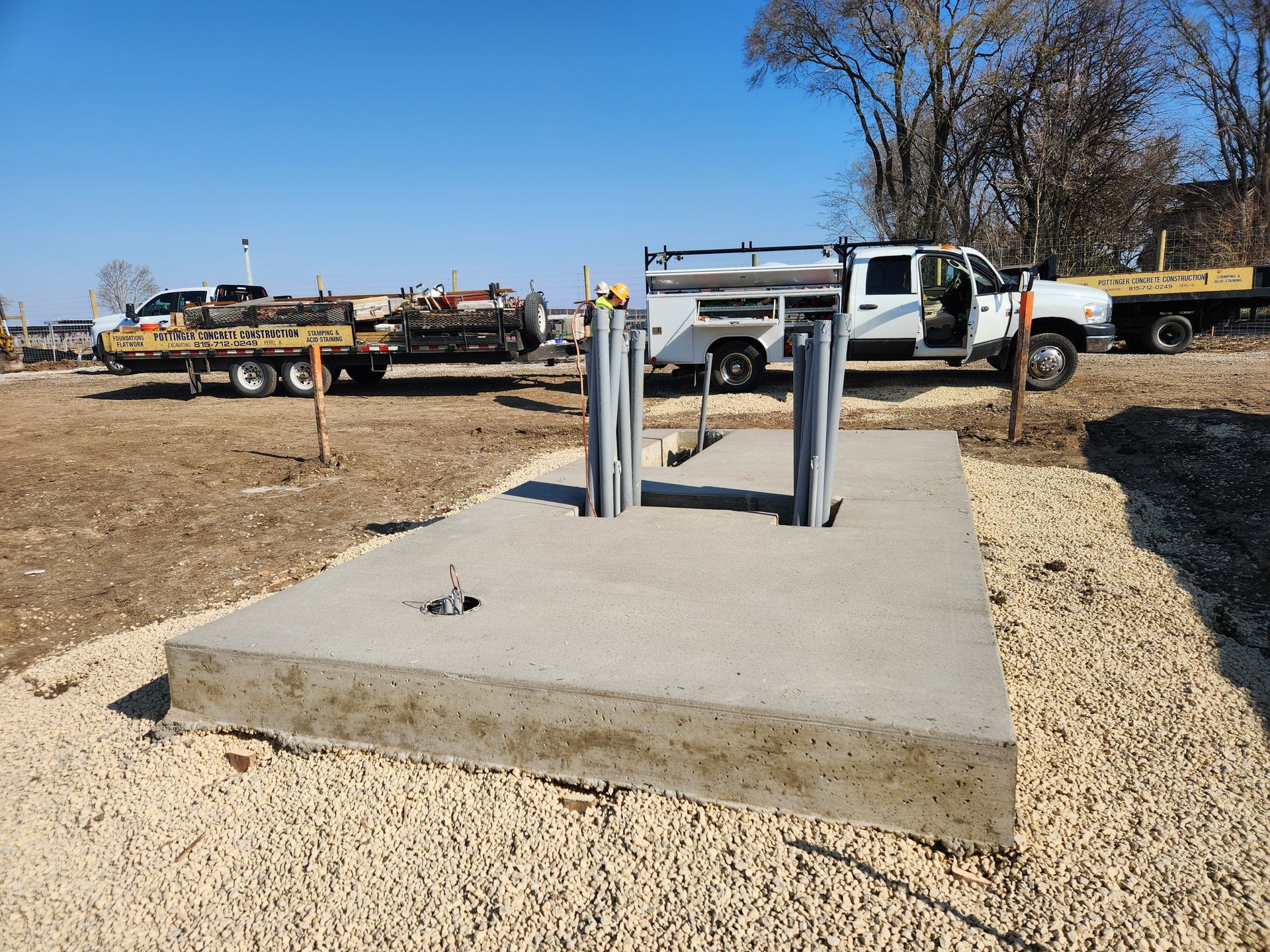A white truck is parked in a gravel lot next to a concrete platform.