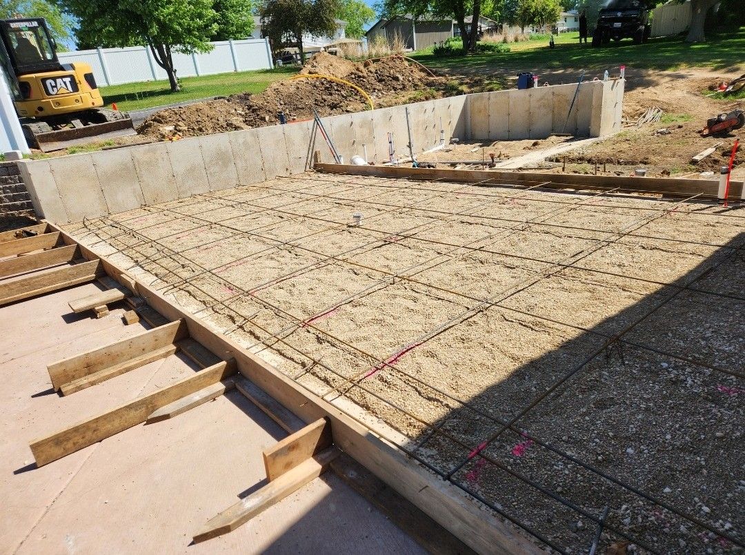 A concrete base for a house is being built in a yard.