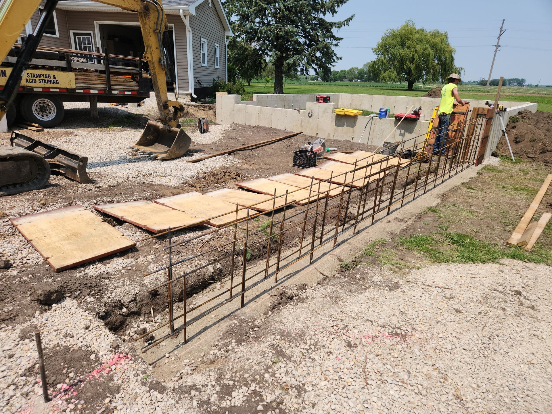 A man is working on a concrete wall in front of a house.