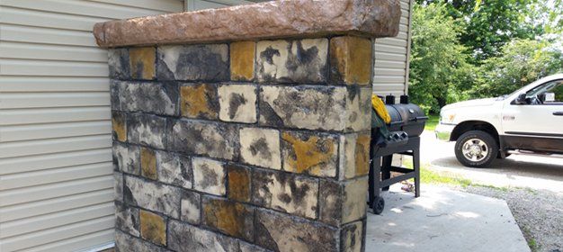 A white truck is parked in front of a brick wall.