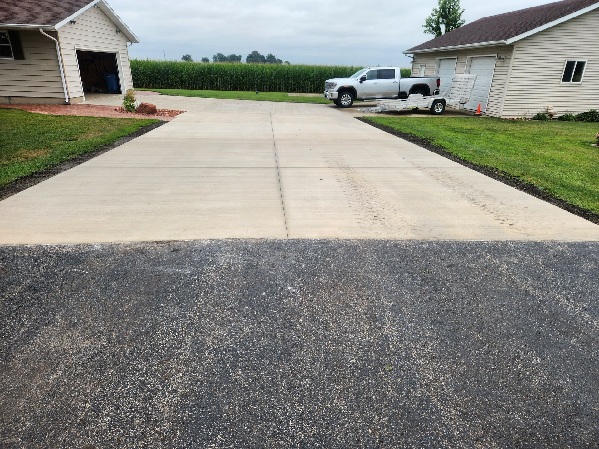 Concrete driveway between two houses with a white pickup truck in the background.