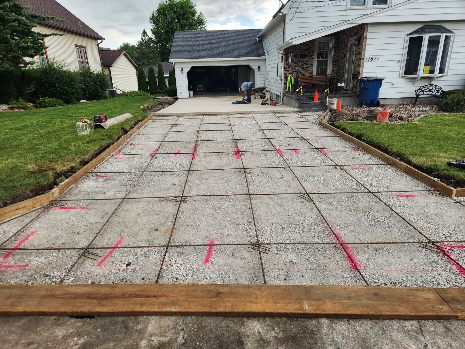Concrete driveway under construction with red layout marks in a suburban home