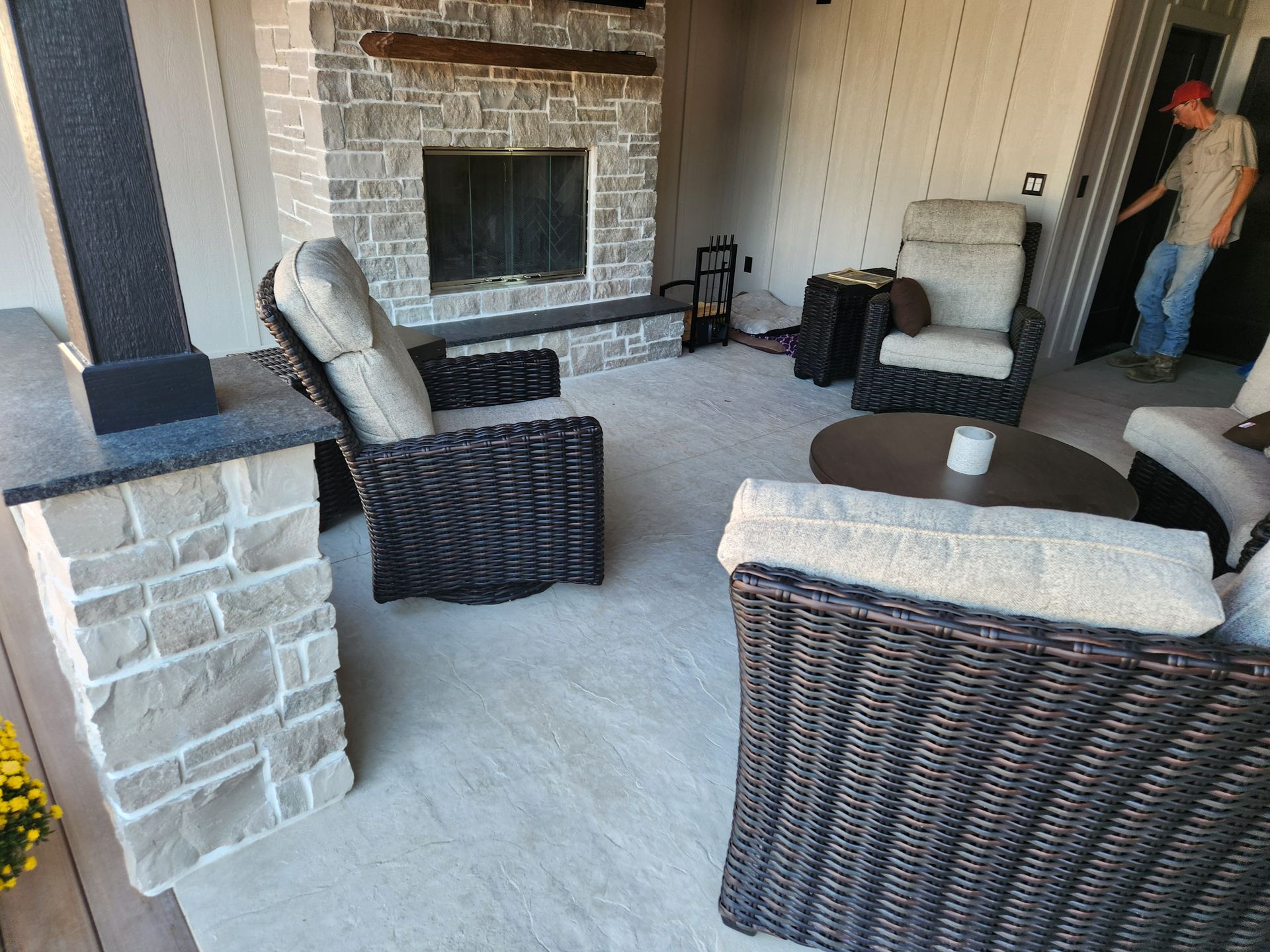 Outdoor seating area with fireplace and person entering a doorway.