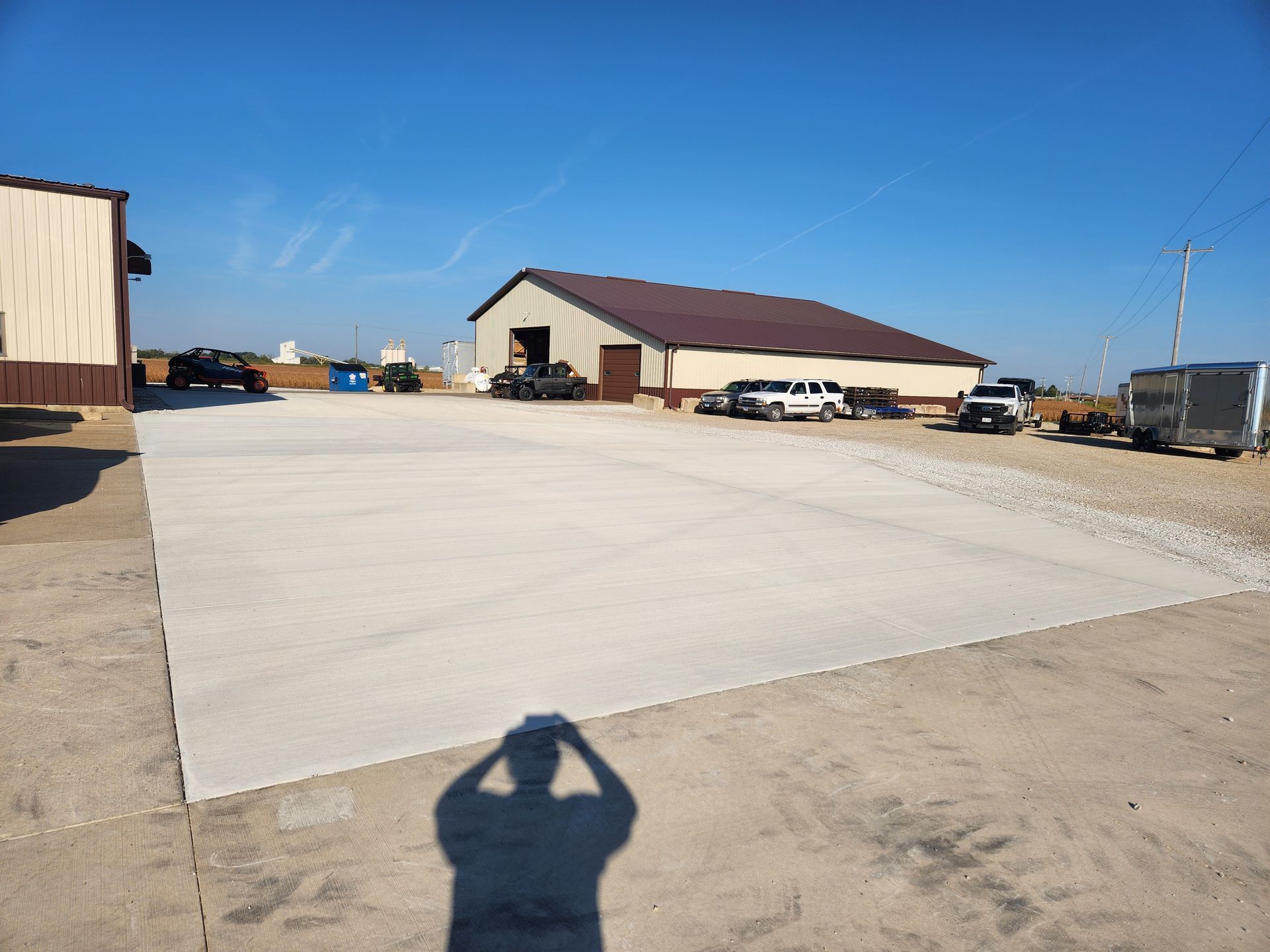 Concrete slab, buildings, vehicles in a sunny outdoor area person's shadow visible.