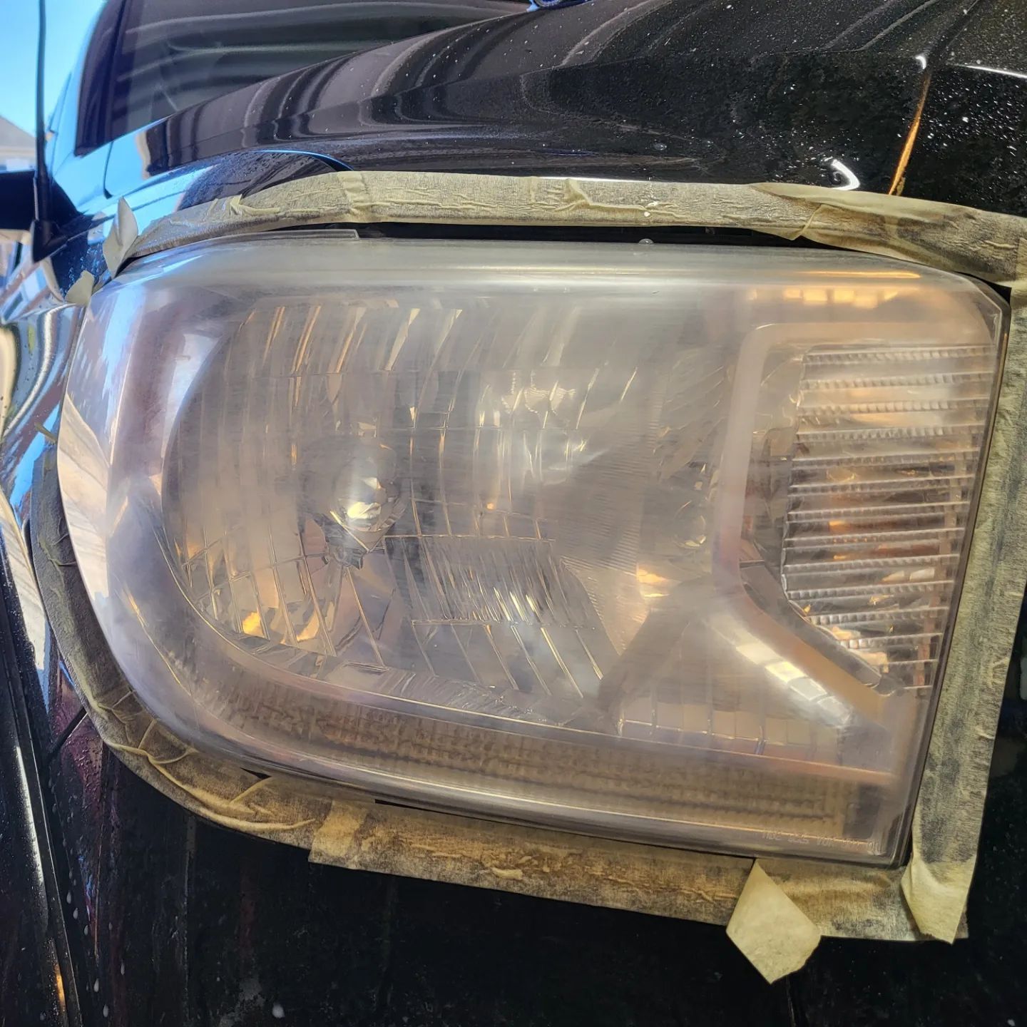 A close up of a car headlight with tape on it.