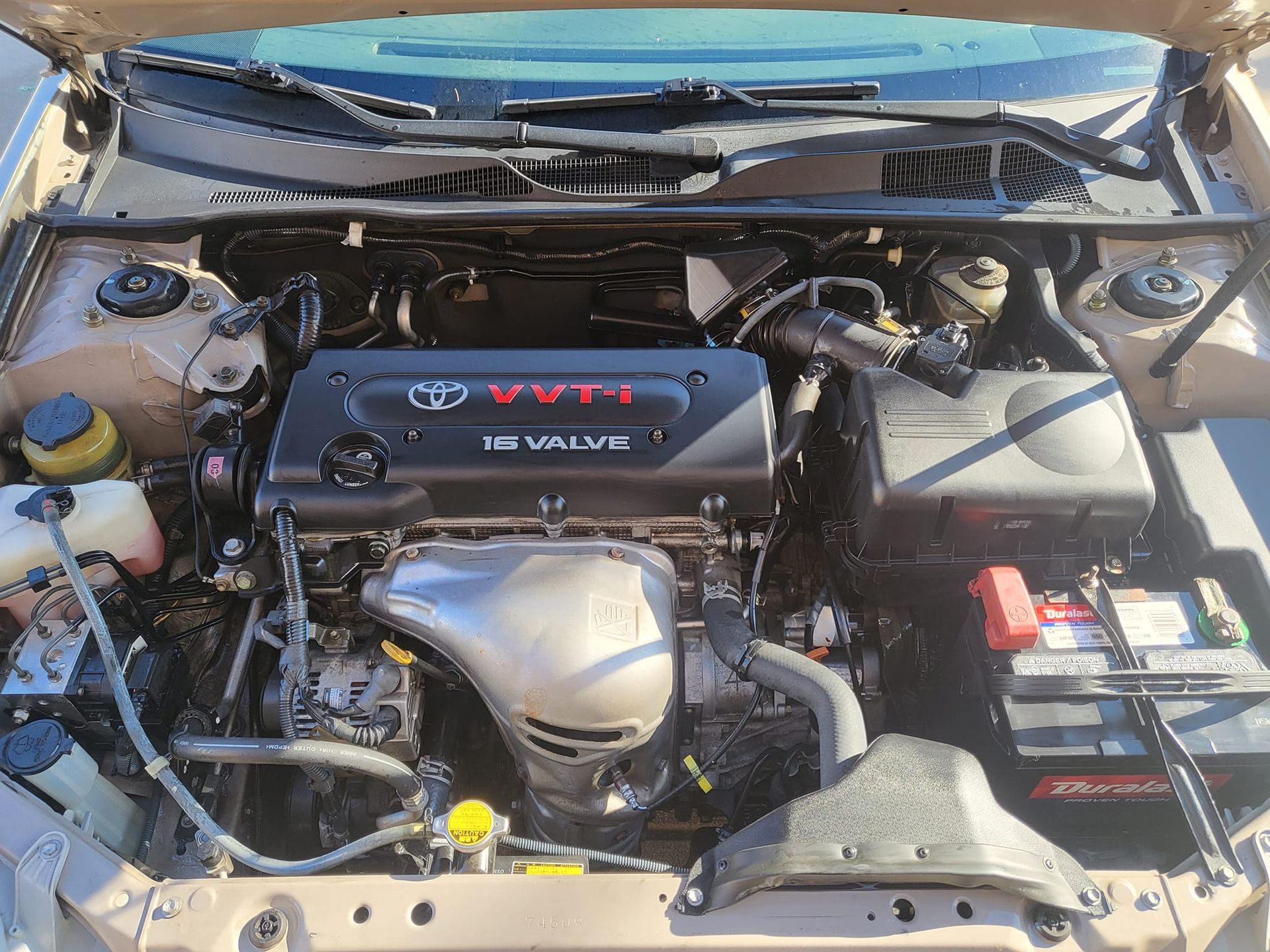 The engine of a toyota camry is shown with the hood up.