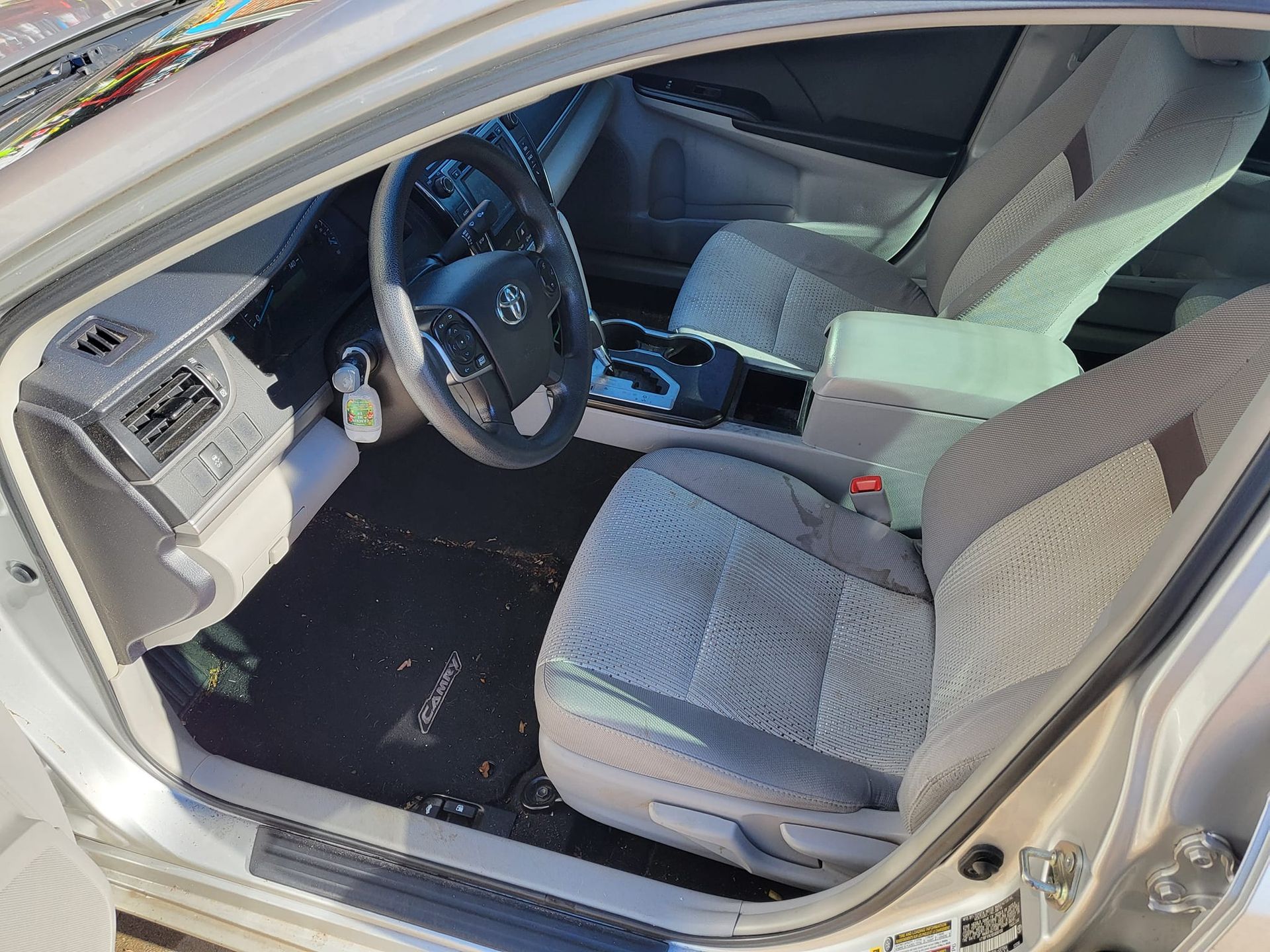 The inside of a car with the door open and the steering wheel visible.