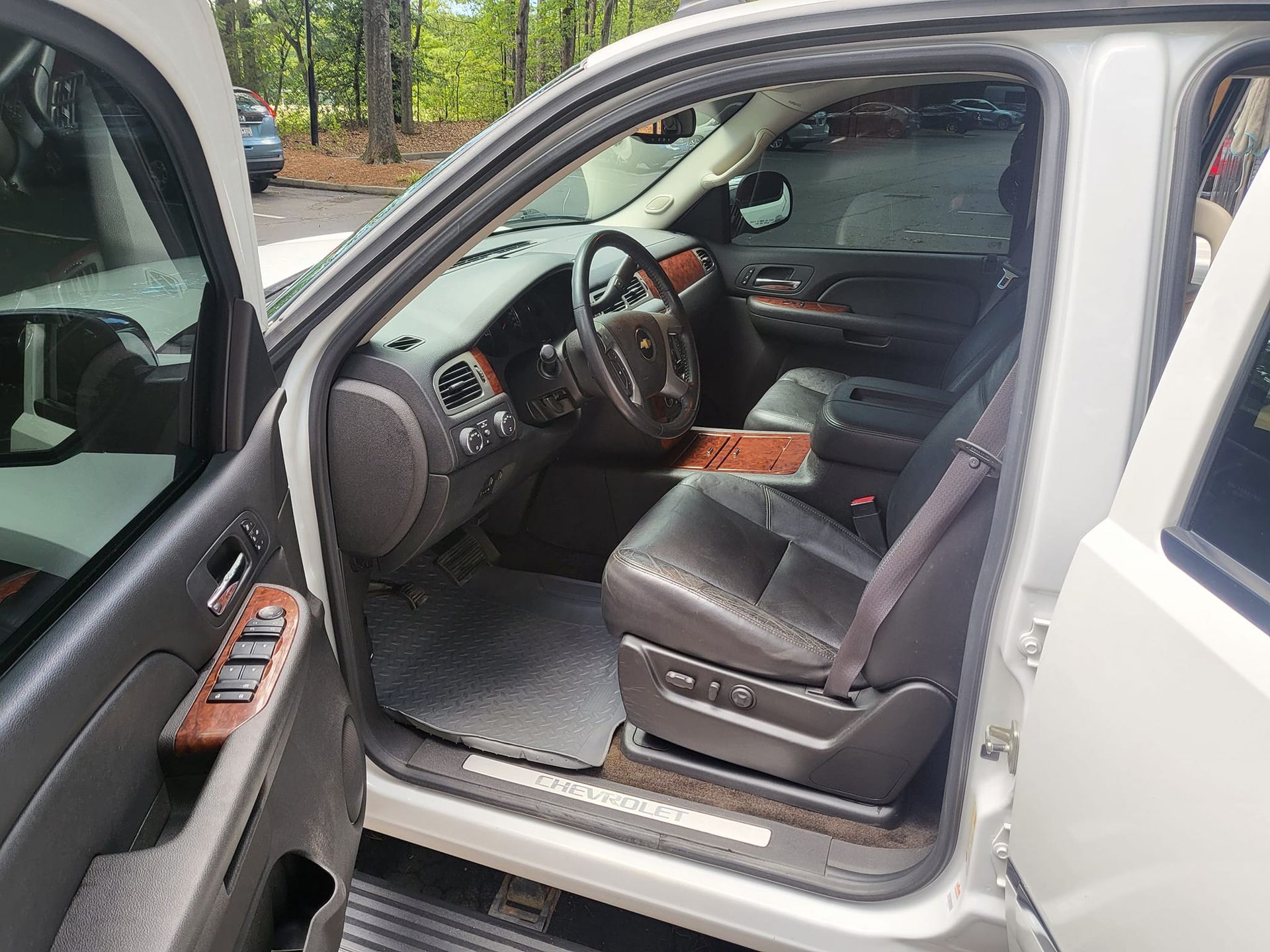 The inside of a white suv with the door open and the steering wheel visible.