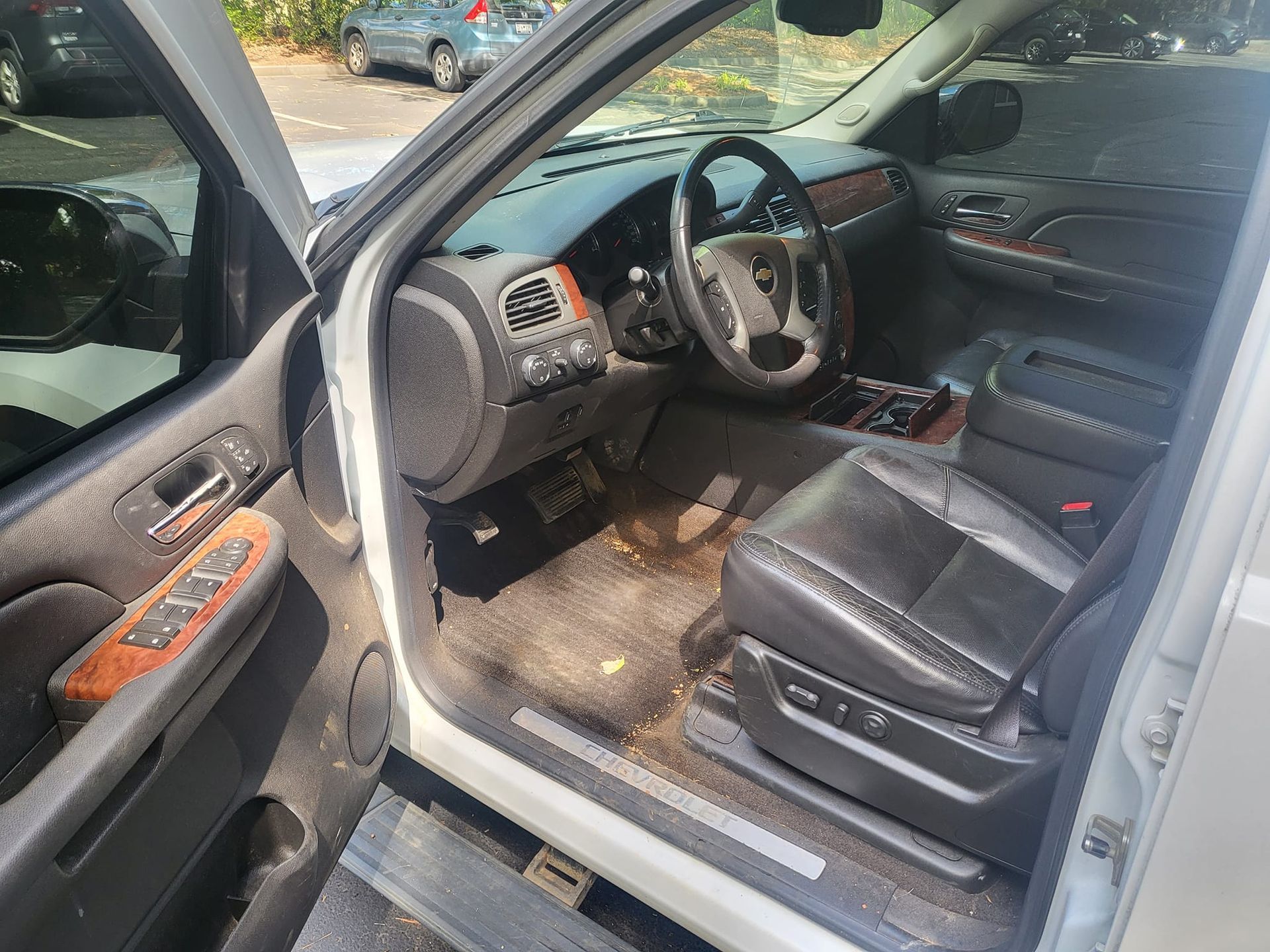 The inside of a car with the door open and the steering wheel visible.