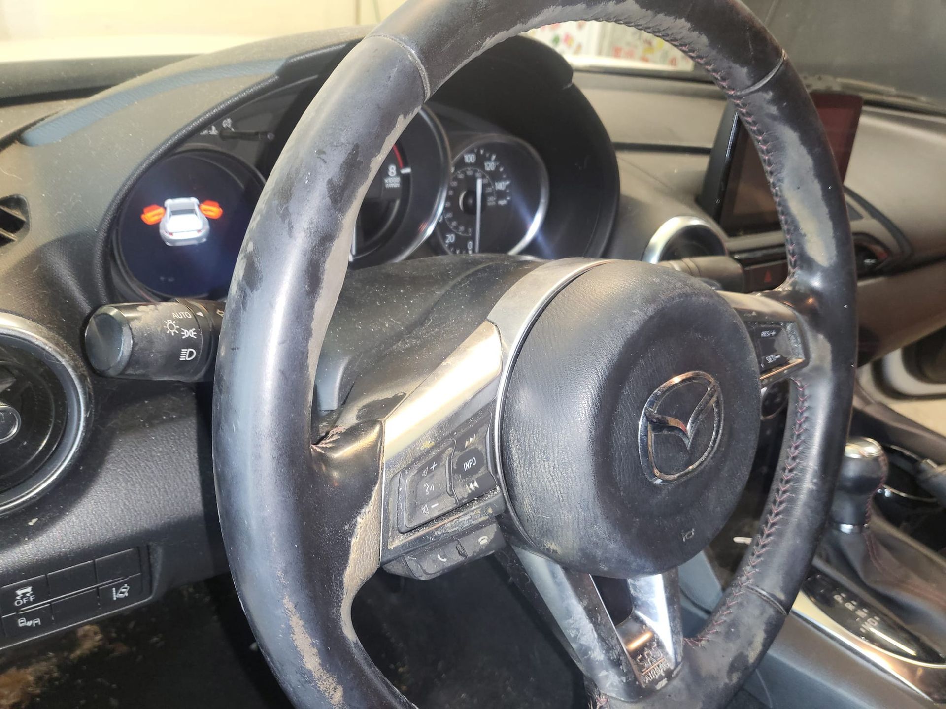 A dirty steering wheel with a mazda logo on it