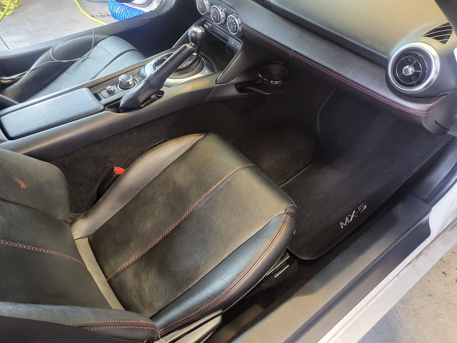 The inside of a car with the door open and the seats removed.