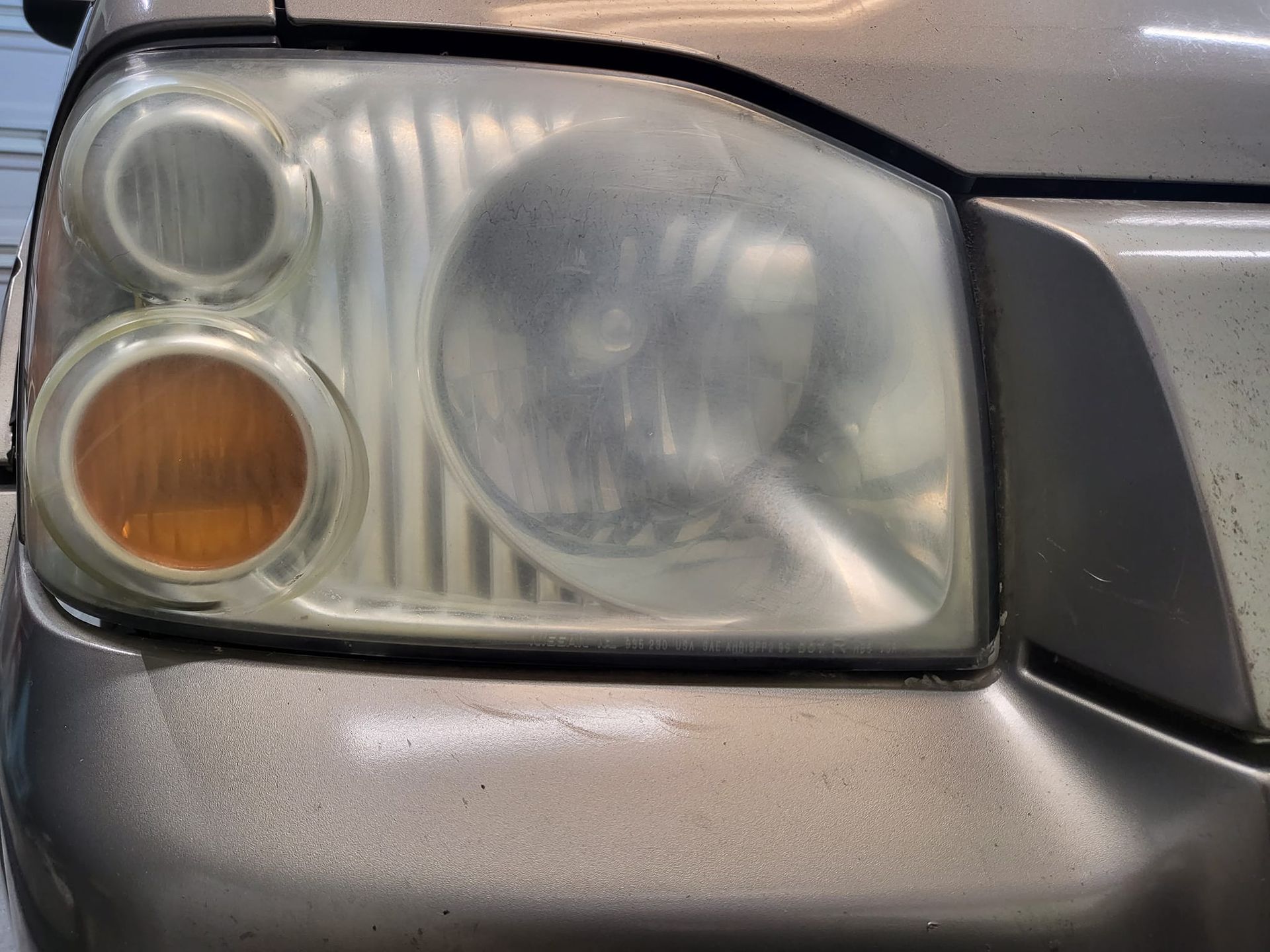 A close up of a dirty headlight on a car.