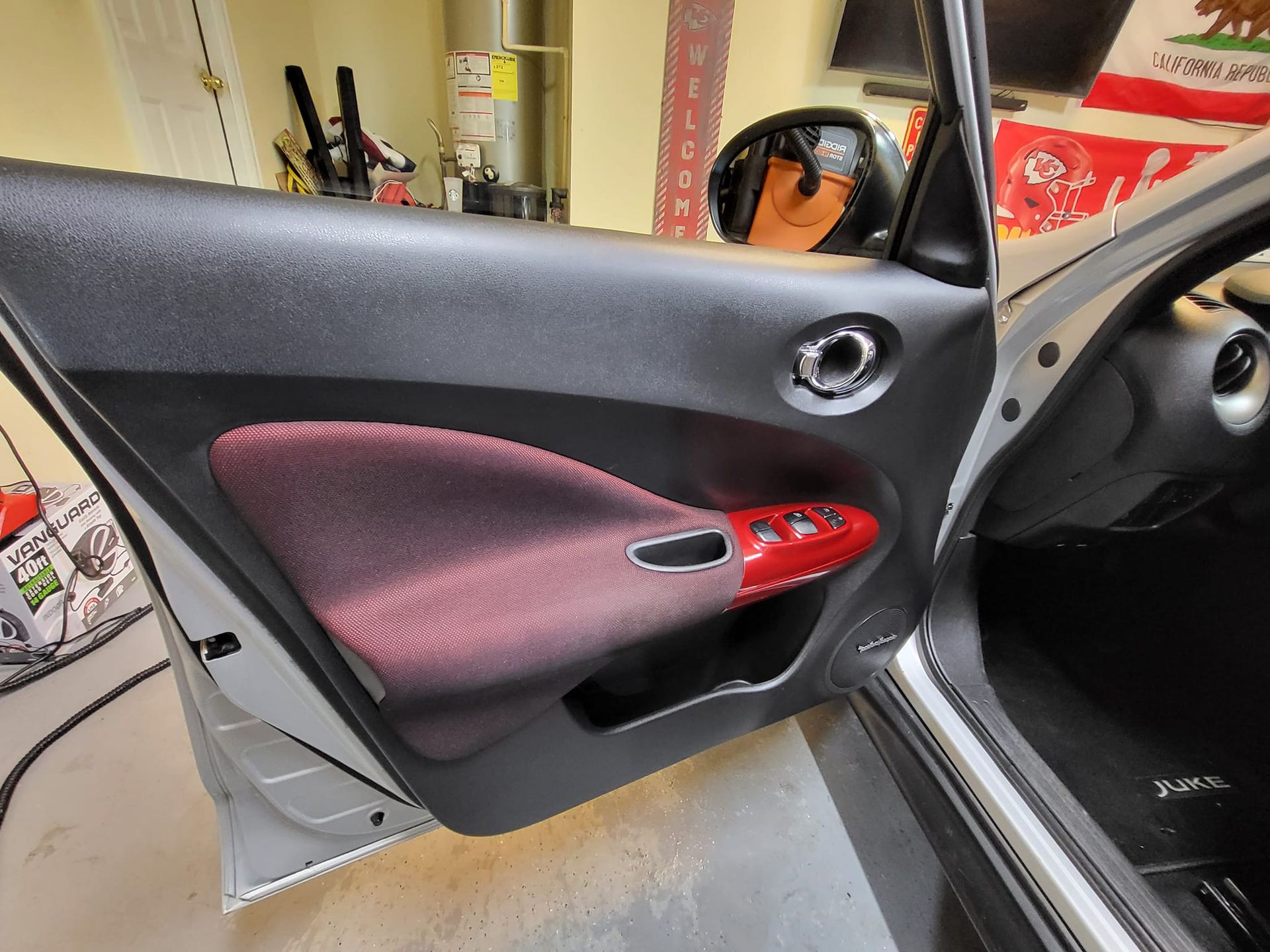 A silver car with the door open in a garage