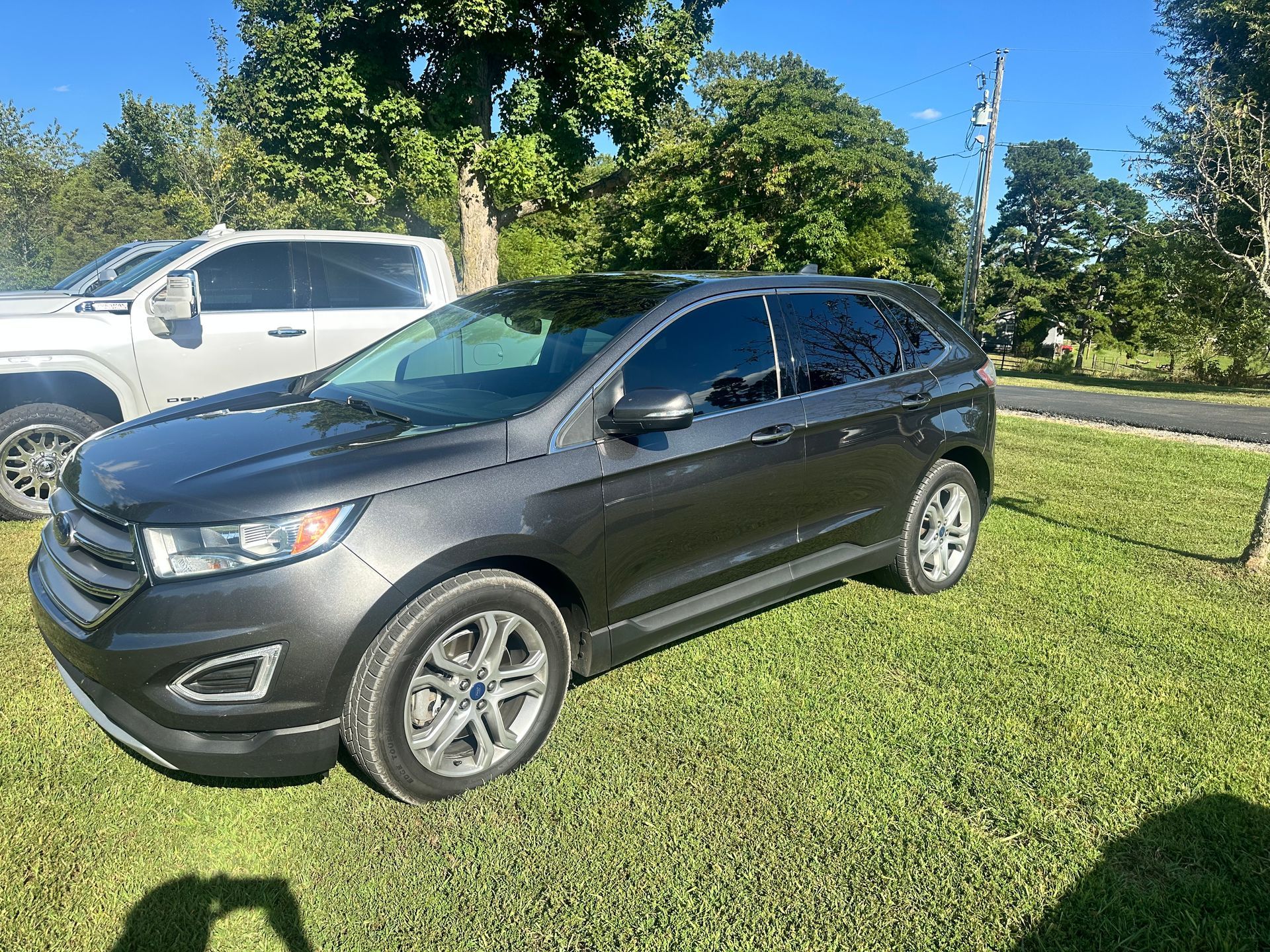 Dark gray Ford Edge SUV parked on grass, daytime.