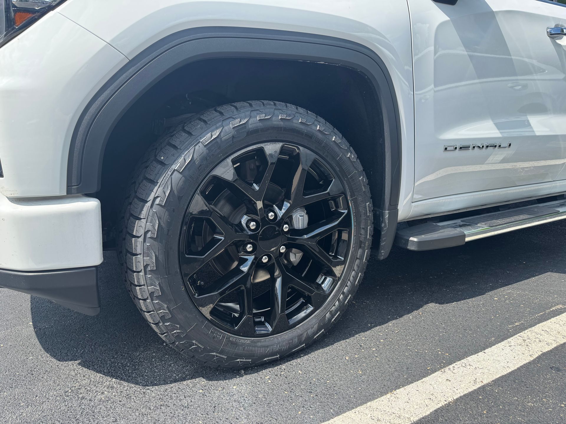White GMC truck with black rims parked on asphalt.